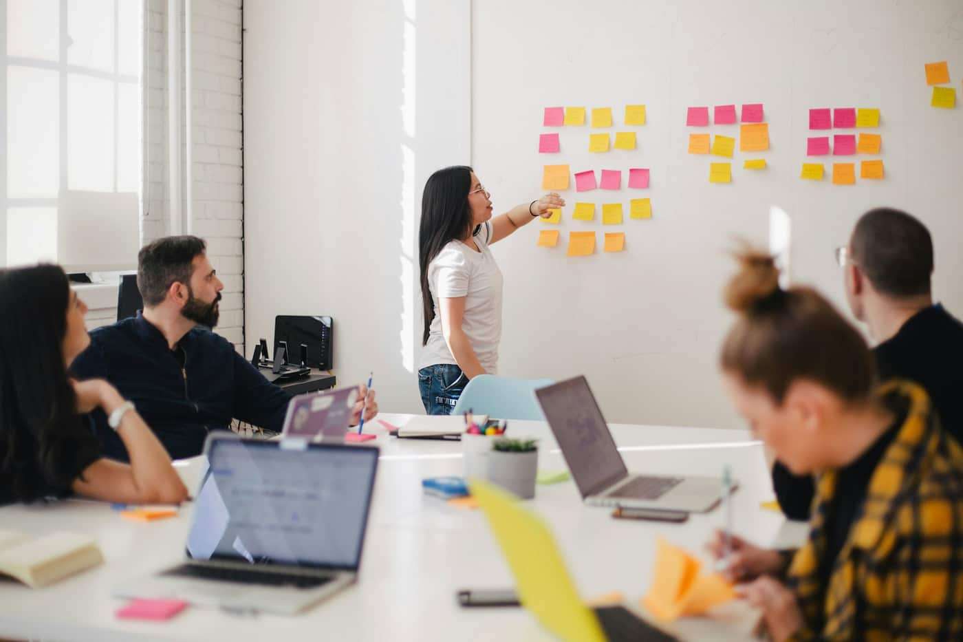 A team in a bright white room working around a long table.